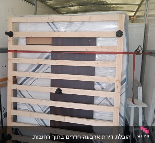 מיטה מעץ קשורה ברצועה בתוך משאית הובלה